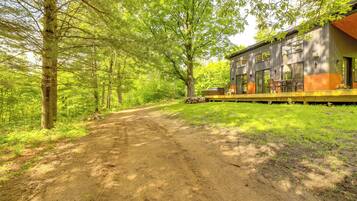 A cabin with a dirt path leading to it, surrounded by trees.