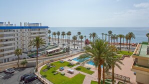Un hotel con piscina, palmeras y vistas al mar.