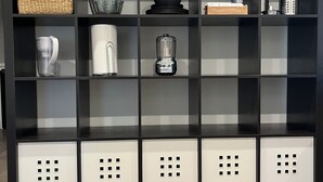 A black shelving unit with kitchen appliances and storage boxes. - Lodge at Concord Lavender Farm. (Concord)