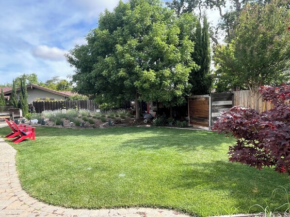 A well-maintained backyard with a lawn, a wooden fence, and a variety of plants.