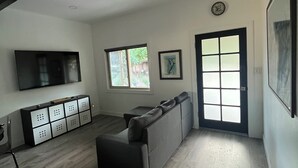 A modern living room with a large TV, a sofa, a coffee table, and a cabinet. - Lodge at Concord Lavender Farm. (Concord)