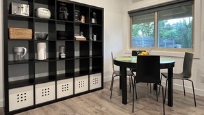 A modern kitchen with a black and white color scheme, featuring a built-in bookshelf, a dining table with chairs, and a window with a view of greenery. - Lodge at Concord Lavender Farm. (Concord)