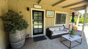 A covered porch with a wicker sofa, a potted plant, a fire extinguisher, and a sign that says "live simply". - Lodge at Concord Lavender Farm. (Concord)