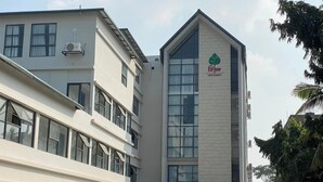 Un edificio moderno con un logotipo verde llamativo en la fachada, ventanas amplias y un techo plano.