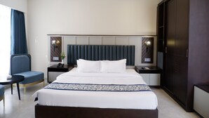 Una habitación de hotel moderna con una cama grande, una mesita de noche, una silla y un armario.