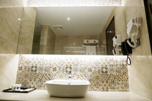 A bathroom with a large mirror, a sink, and a towel rack.