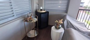 A balcony with a covered seating area, a small table with a vase, and a side table with a lamp. - Starfish Beach House (Agnes Water)