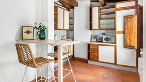 A kitchen with a wooden ceiling, white walls, and a tiled floor. There is a table with two chairs, a microwave, and a cabinet. - GuestHost - Charming 75 sqm apartment, able to accommodate up to 4 people, located on the FOURTH floor of an ancient building (NO lift). The property is located in the historic center of Florence (Restricted Traffic Area), in the lively Sant'Ambrogio dis (Firenze)