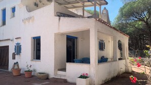 A white building with a covered patio, potted plants, and a small garden area. - Splendid detached villa, near the sea (Santa Lucia)