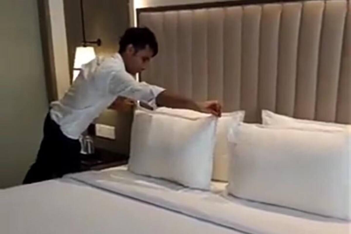 A neatly made bed with white linens in a hotel room.