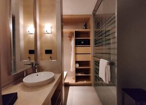 Een moderne badkamer met een grote spiegel, een rond wastafel en een douchecabine van glas.