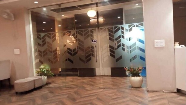 A reception area with a herringbone patterned floor, a seating area with a sofa and chairs, and a potted plant. - Hotel Rajvanshi (Gurugram)