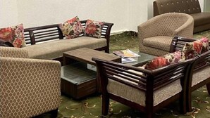 A modern lounge area with sofas, armchairs, and a coffee table. - Hotel Rajvanshi (Gurugram)