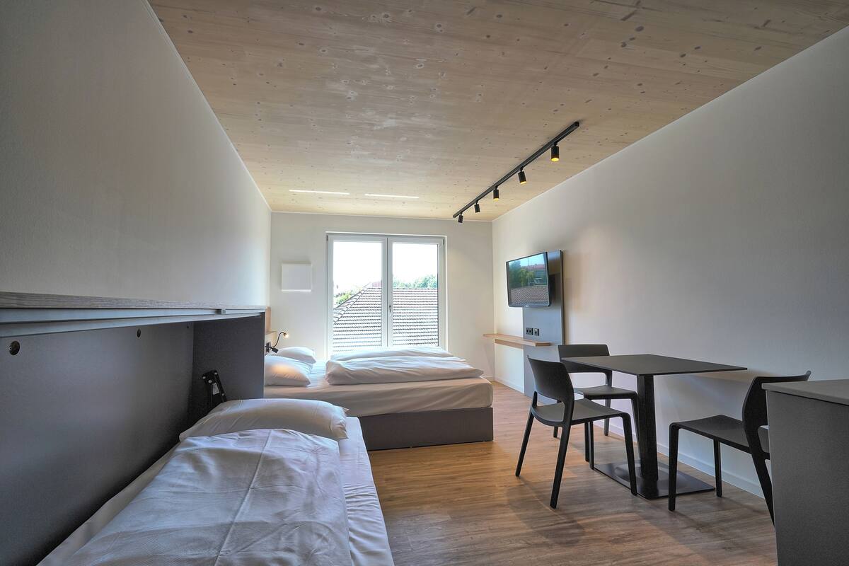 Ein modernes Zimmer mit Bett, Schreibtisch und Fernseher.