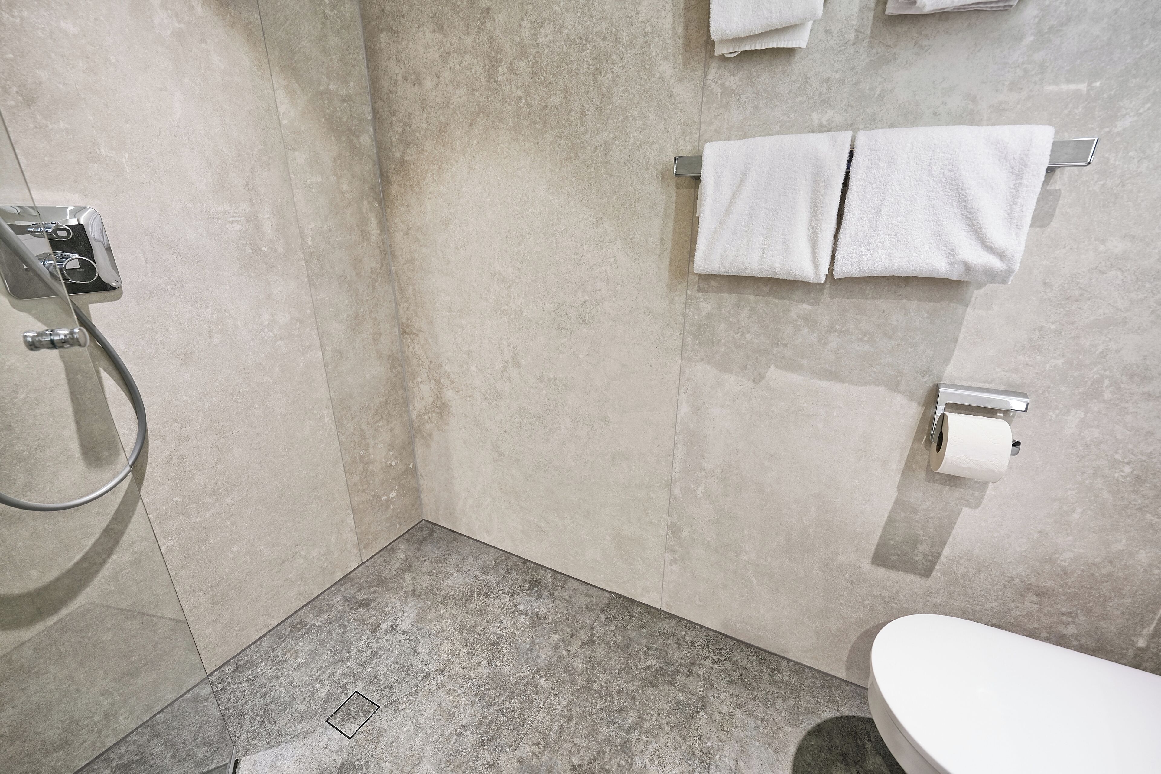 A bathroom with a shower, toilet, and towel rack.