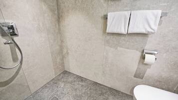 A bathroom with a shower, toilet, and towel rack.