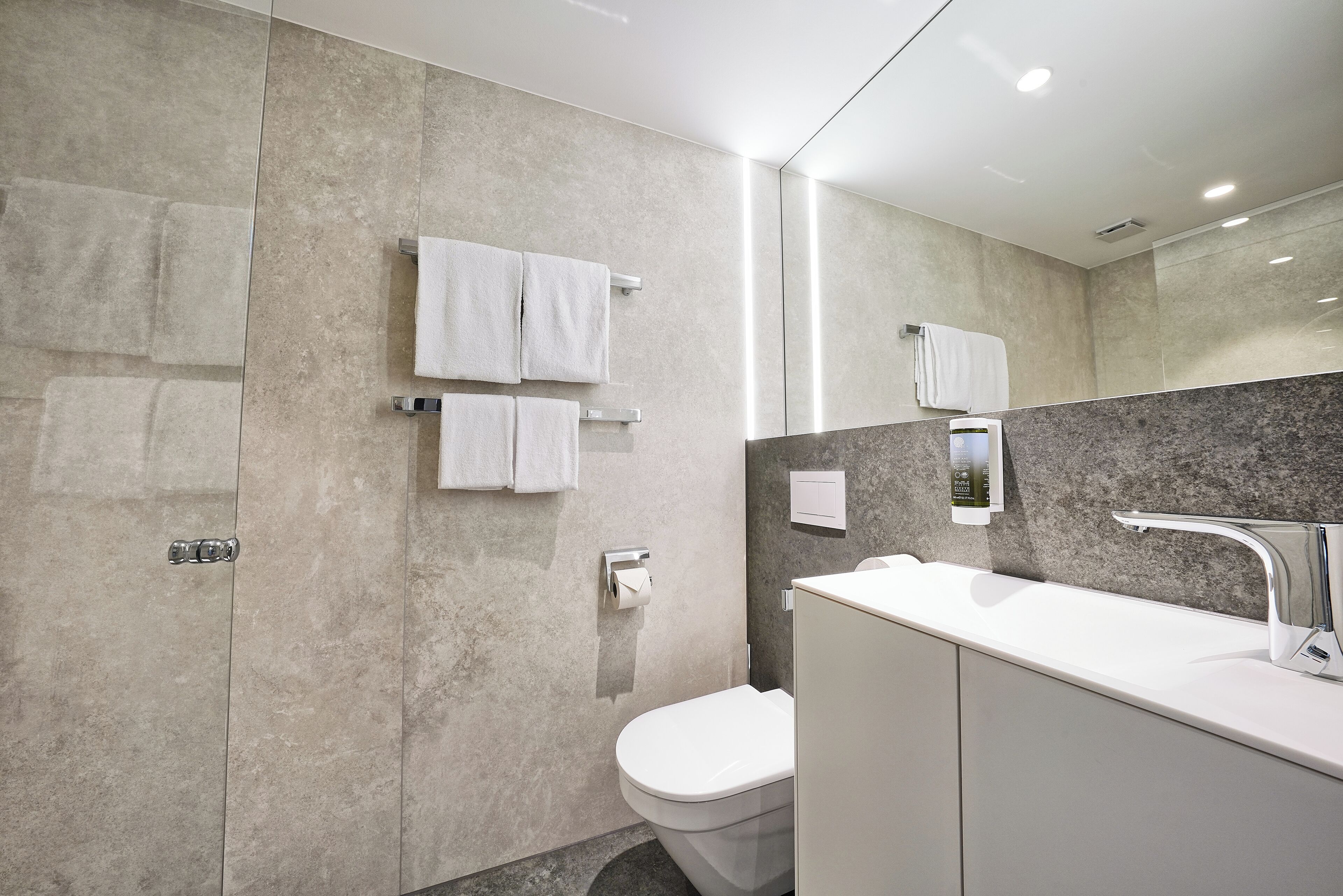 A modern bathroom with a toilet, sink, and towel rack.
