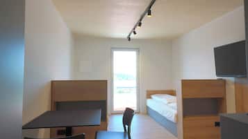 A modern room with a desk, chair, bunk beds, and a TV.