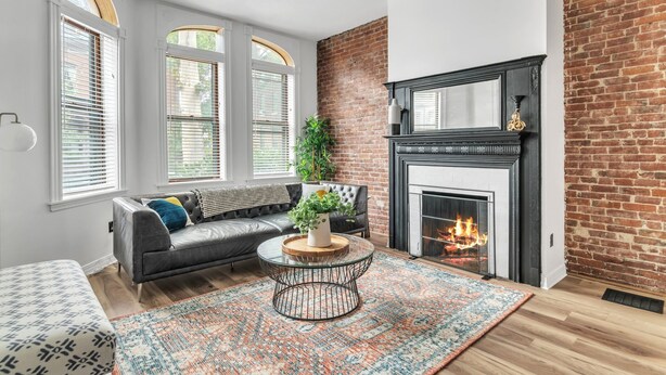 A living room with a fireplace, a sofa, a coffee table, and a patterned rug. - The Smith Victorian 2BR Brownstone Apartment (Springfield)