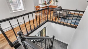 A modern interior with a staircase, hardwood floors, and a dining area with a table and chairs. - The Smith Victorian 2BR Brownstone Apartment (Springfield)