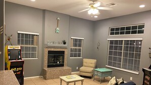 A living room with a fireplace, a racquetball arcade, and a ceiling fan. - As new Santa Fe home, over 2000sf, 4 bedrooms, 2 bathrooms, Pool, Spa. (La Quinta)