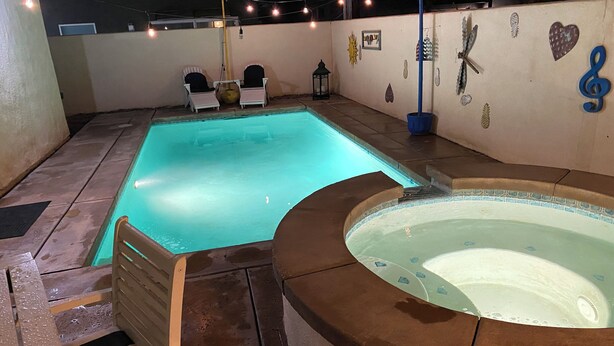A swimming pool with a hot tub, string lights, and decorative wall art. - As new Santa Fe home, over 2000sf, 4 bedrooms, 2 bathrooms, Pool, Spa. (La Quinta)