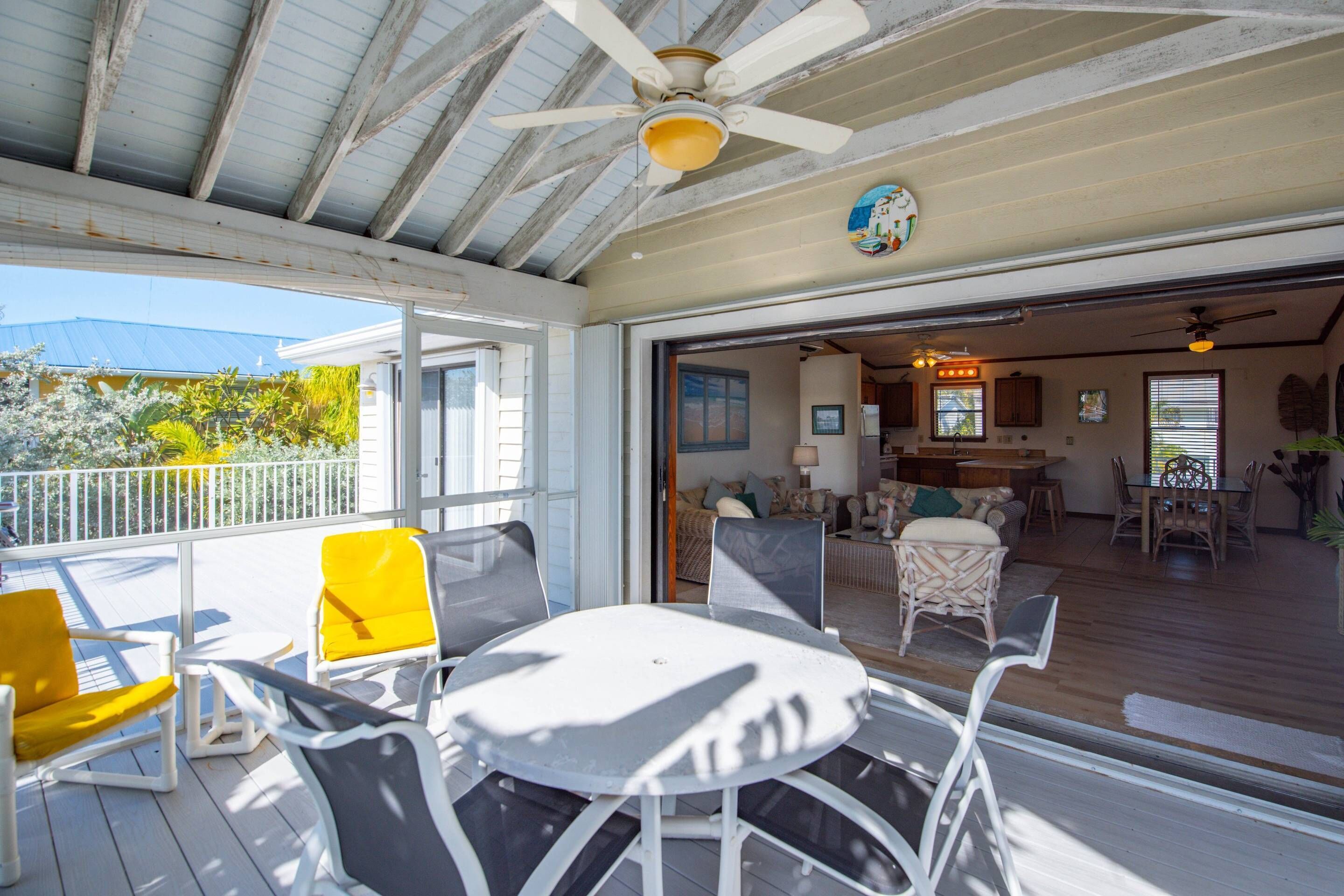 An open deck with outdoor seating, a ceiling fan, and a view into the house.