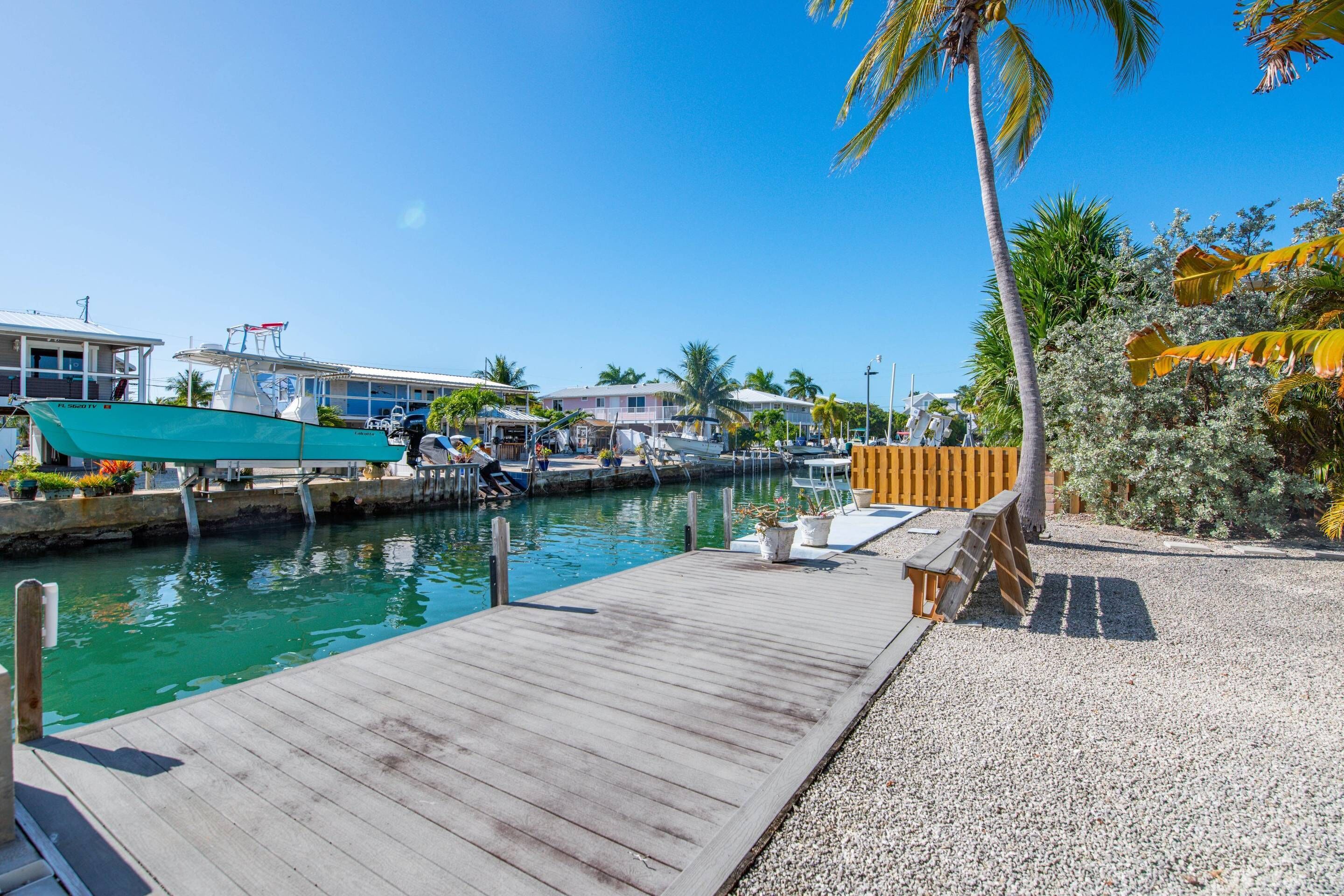 A marina with a wooden dock, boats, and a small building with a covered area.