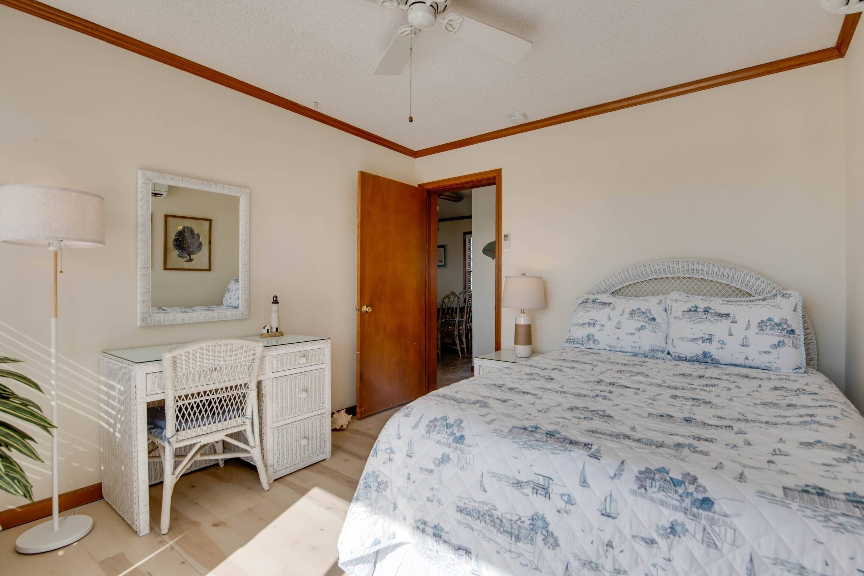A bedroom with a bed, dresser, chair, and a ceiling fan.