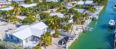 An aerial view of a coastal residential area with houses, a marina, and a clear view of the ocean.