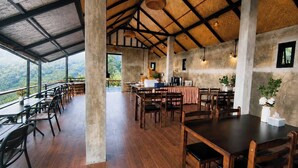 Un comedor amplio con techos altos, suelo de madera y grandes ventanales con vistas al paisaje circundante.