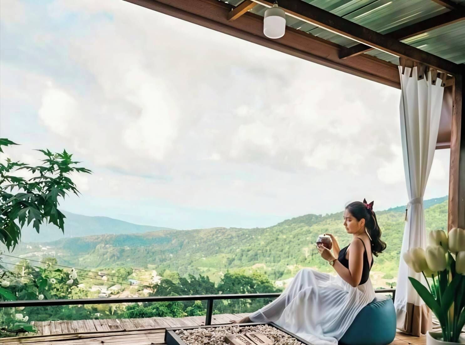 A person sitting on a balcony with a view of a green landscape.
