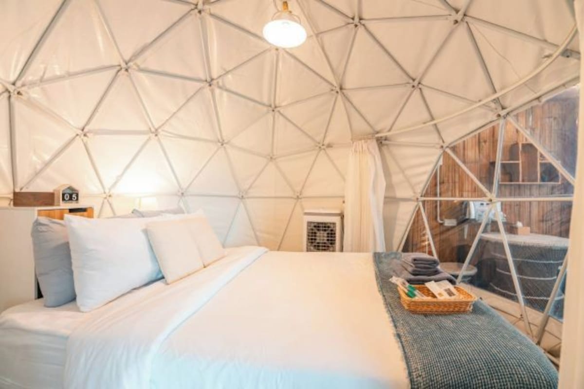 A tented accommodation with a bed, a small table, and a window.