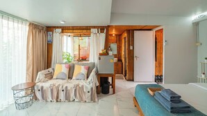 Una habitación con sofá, cama, una mesita y un baño visible a través de una puerta abierta.