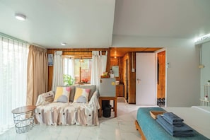 Una habitación con sofá, cama, una mesita y un baño visible a través de una puerta abierta.