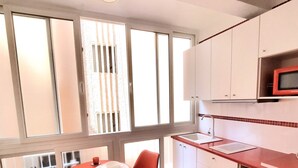 Une cuisine avec un coin repas, de grandes fenêtres et une chaise rouge.