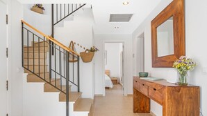 A modern interior with a wooden staircase, a wooden console table, and a large mirror. - Villa Pepponi MENORCA modern, private pool, AC (Sant Lluís)