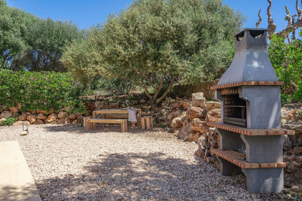 Un área de estar al aire libre con pared de piedra, banco de madera y chimenea de piedra.