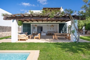 Ein moderner Außenbereich mit Pool, Holzmöbeln und einer Pergola.
