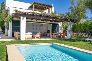 A modern house with a pool, outdoor seating, and a pergola.