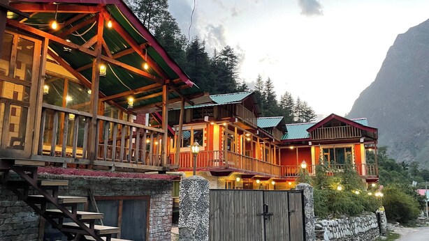 Un bâtiment à plusieurs étages, de style chalet, doté de balcons en bois et d’une entrée surmontée d’un mur en pierre.