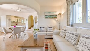 A modern living room with a sofa, coffee table, and dining area.