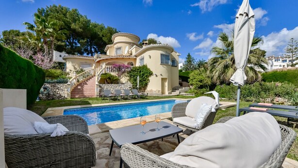 A poolside area with wicker furniture, a glass table, and a white umbrella.