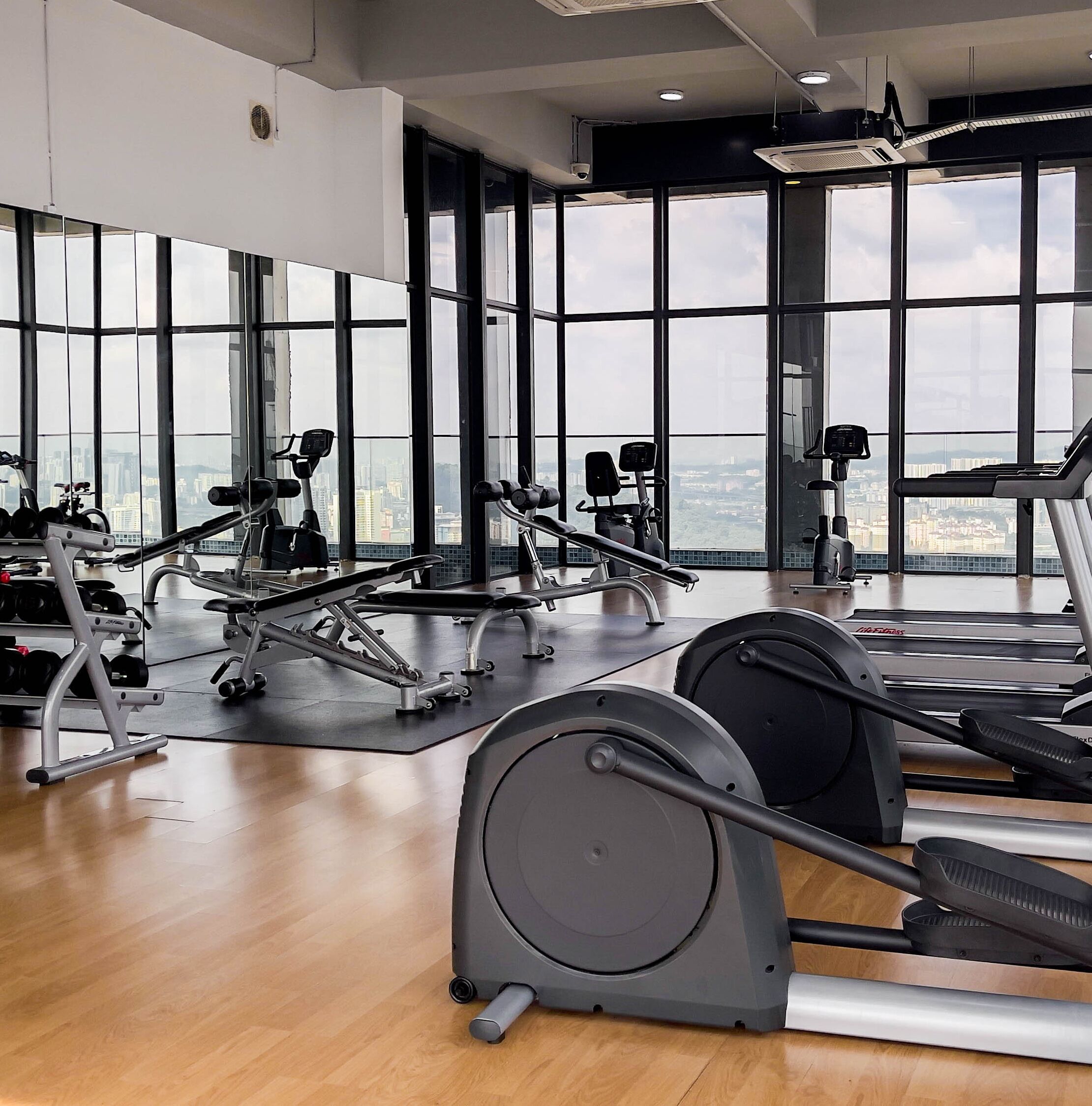 A gym with various exercise equipment, large windows, and a city view.