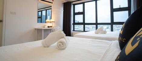 A hotel room with two beds, a bathroom with a mirror, and a window with a city view.