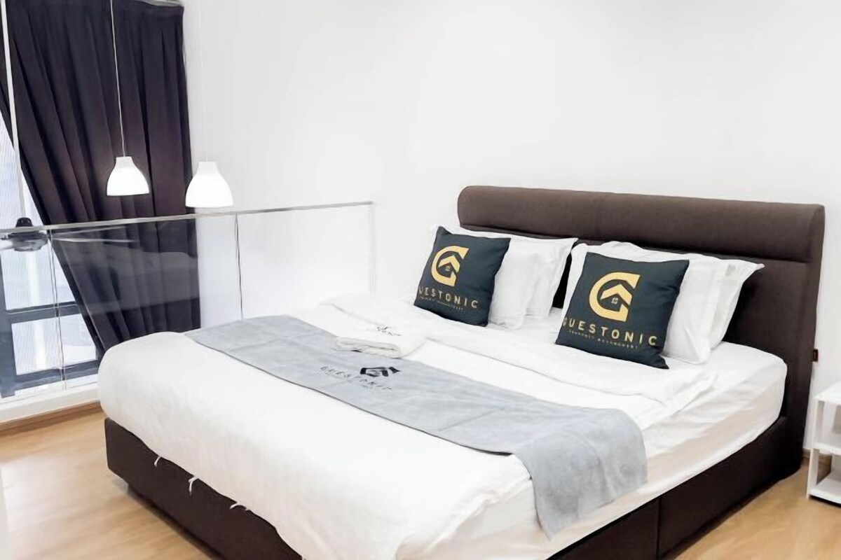 Moderni hotellihuone, jossa on suuri sänky, lasiseinä ja näkymä kaupunkiin.