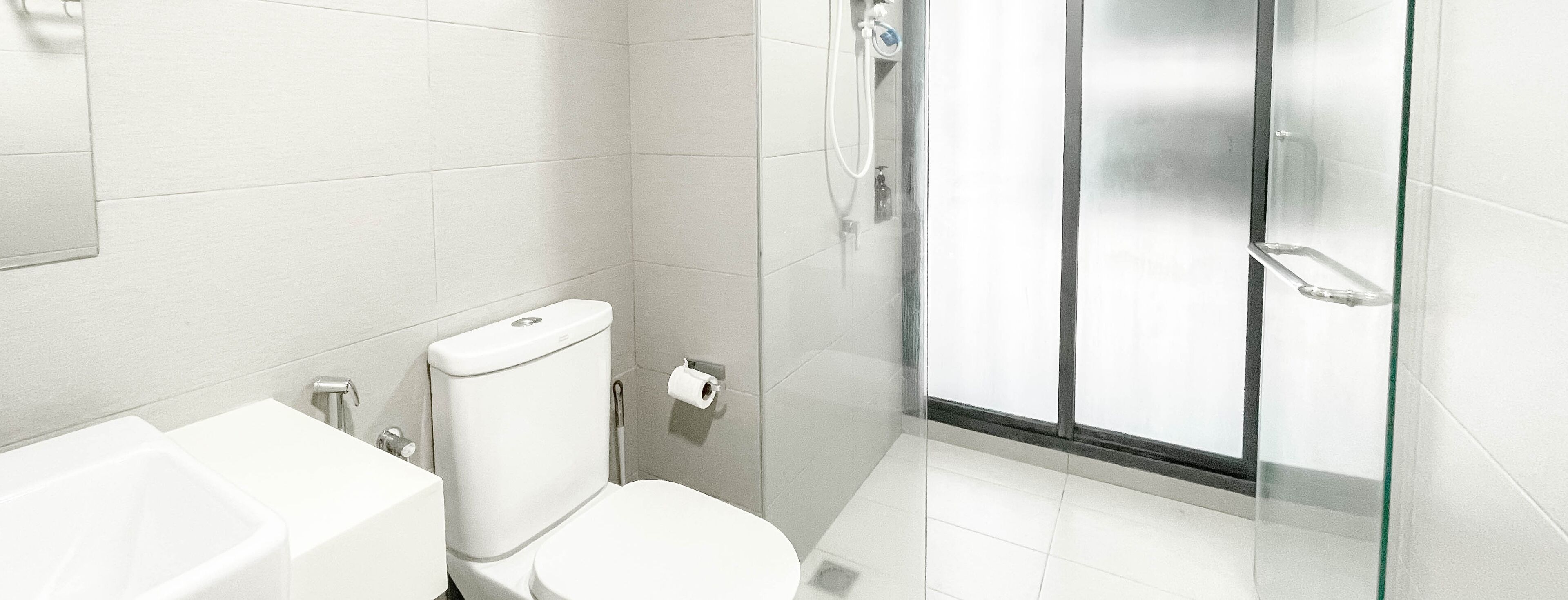 A modern bathroom with a toilet, sink, and glass-enclosed shower.
