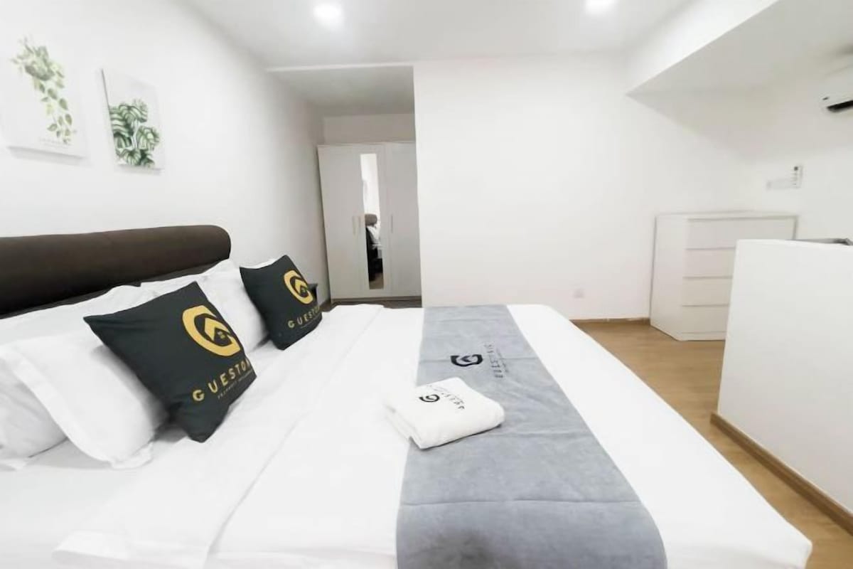 Una habitación de hotel con cama, mesita de noche, armario y puerta que da a otra habitación.