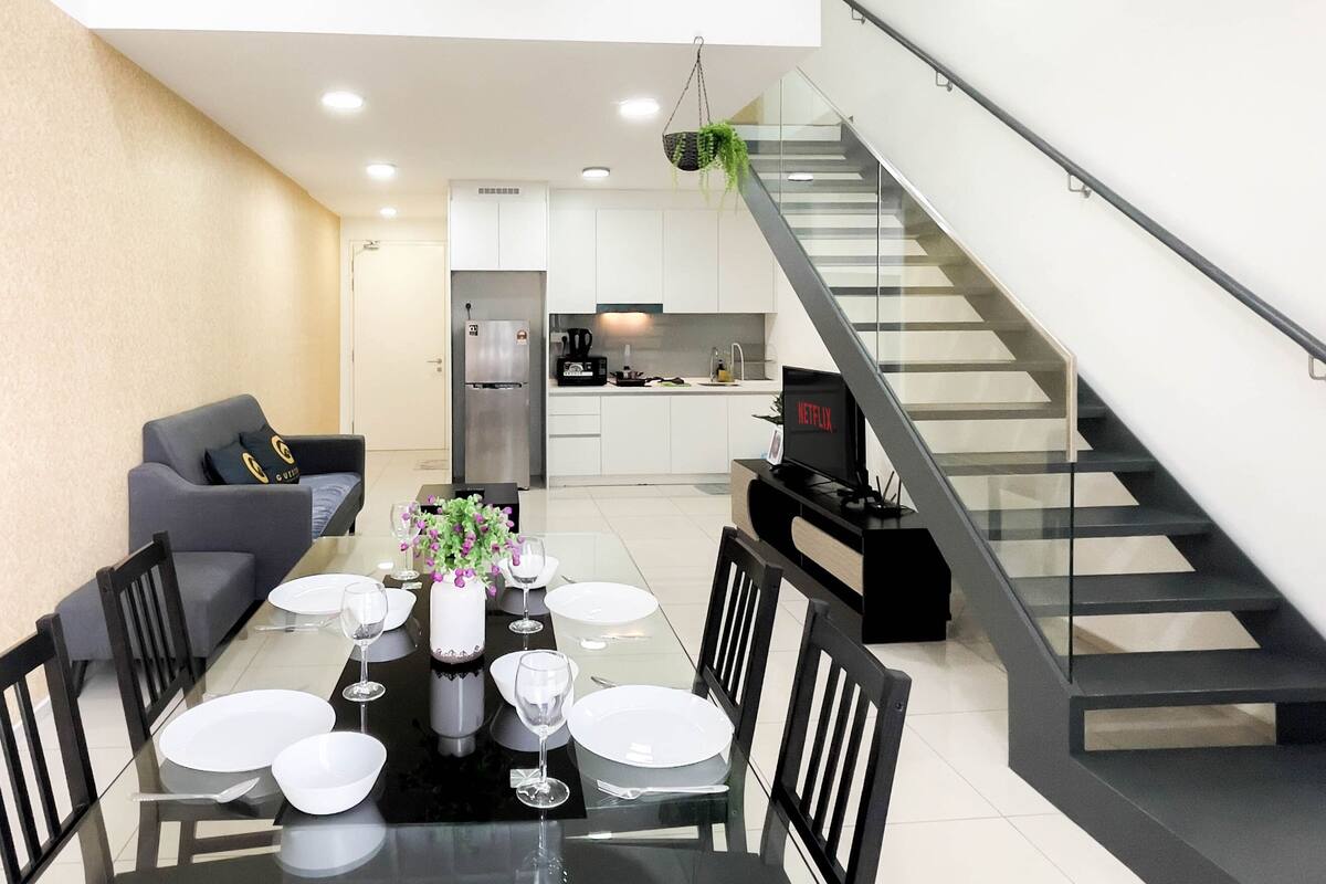 Un espace de vie moderne comprenant un coin repas, une cuisine et un escalier.
