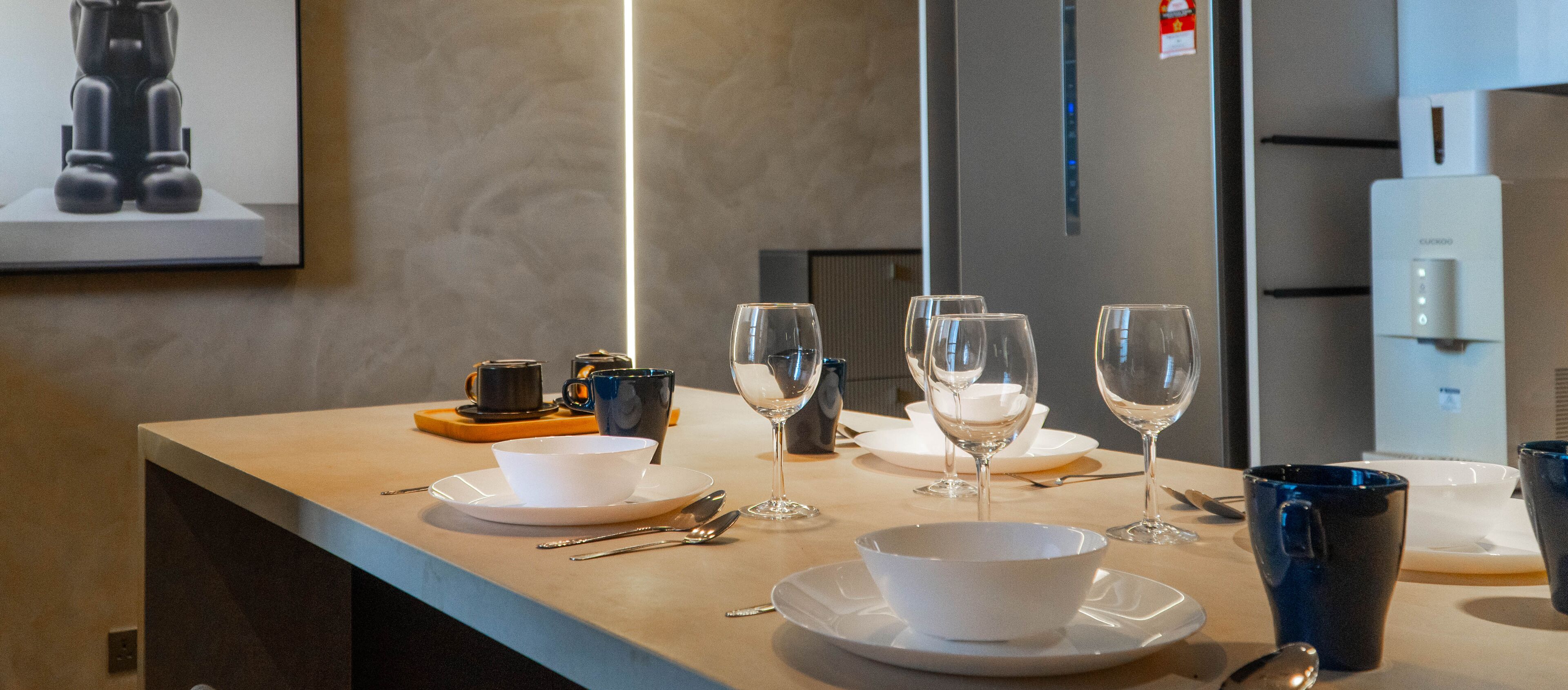 A dining area with a table set for four, including plates, bowls, wine glasses, and cutlery.